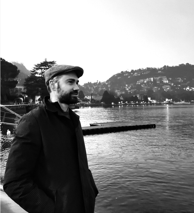 Andrea Anfossi, amministratore di condominio, ritratto in bianco e nero con un panorama lacustre sullo sfondo.